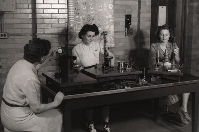 historical image of three women using scientific instruments