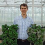 Charles Krasnow in a greenhouse with plants