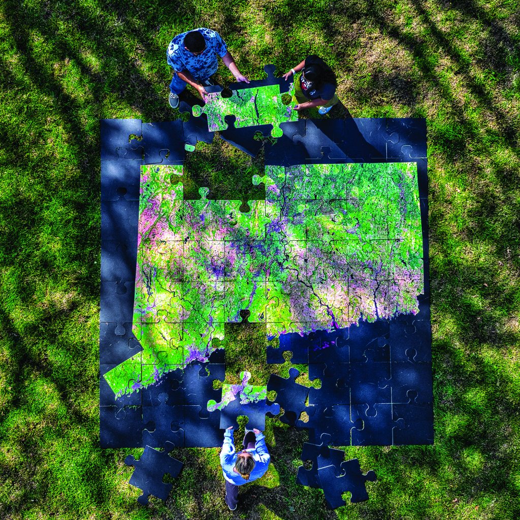 three students putting together a large puzzle of the state of Connecticut